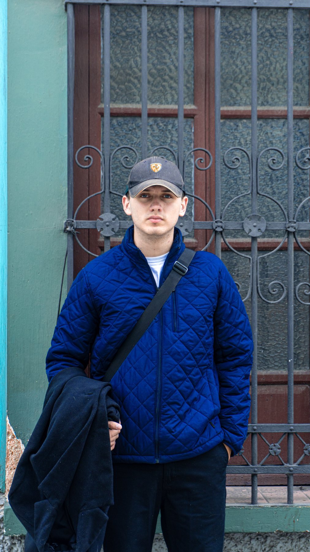 Modelo con chaqueta azul frente a ventana con reja
